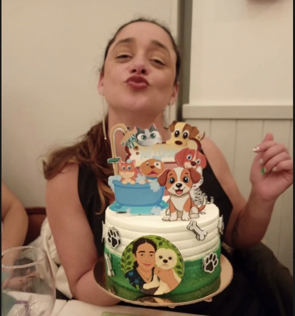 Julieta com o bolo do seu aniversário, decorado com a identidade da Julie’s Groomer